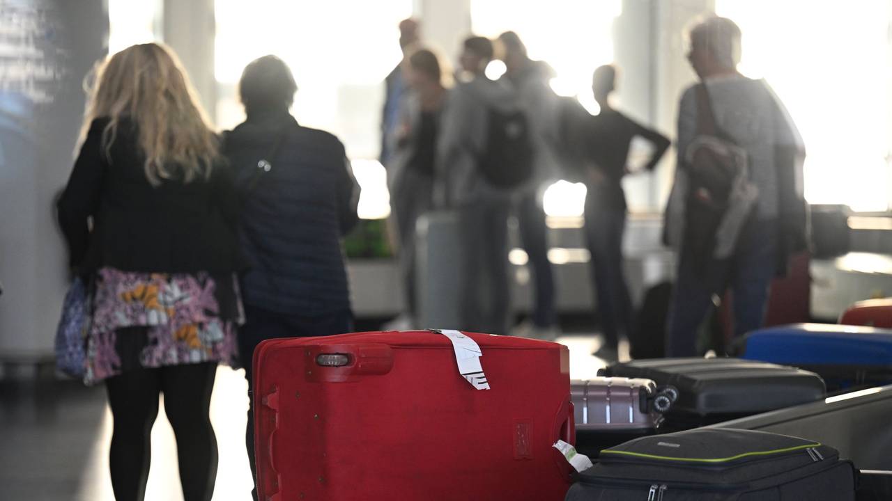 Passagiere warten nach ihrer Ankunft auf dem Konrad-Adenauer-Flughafen am Gepäckband auf ihre Koffer.
