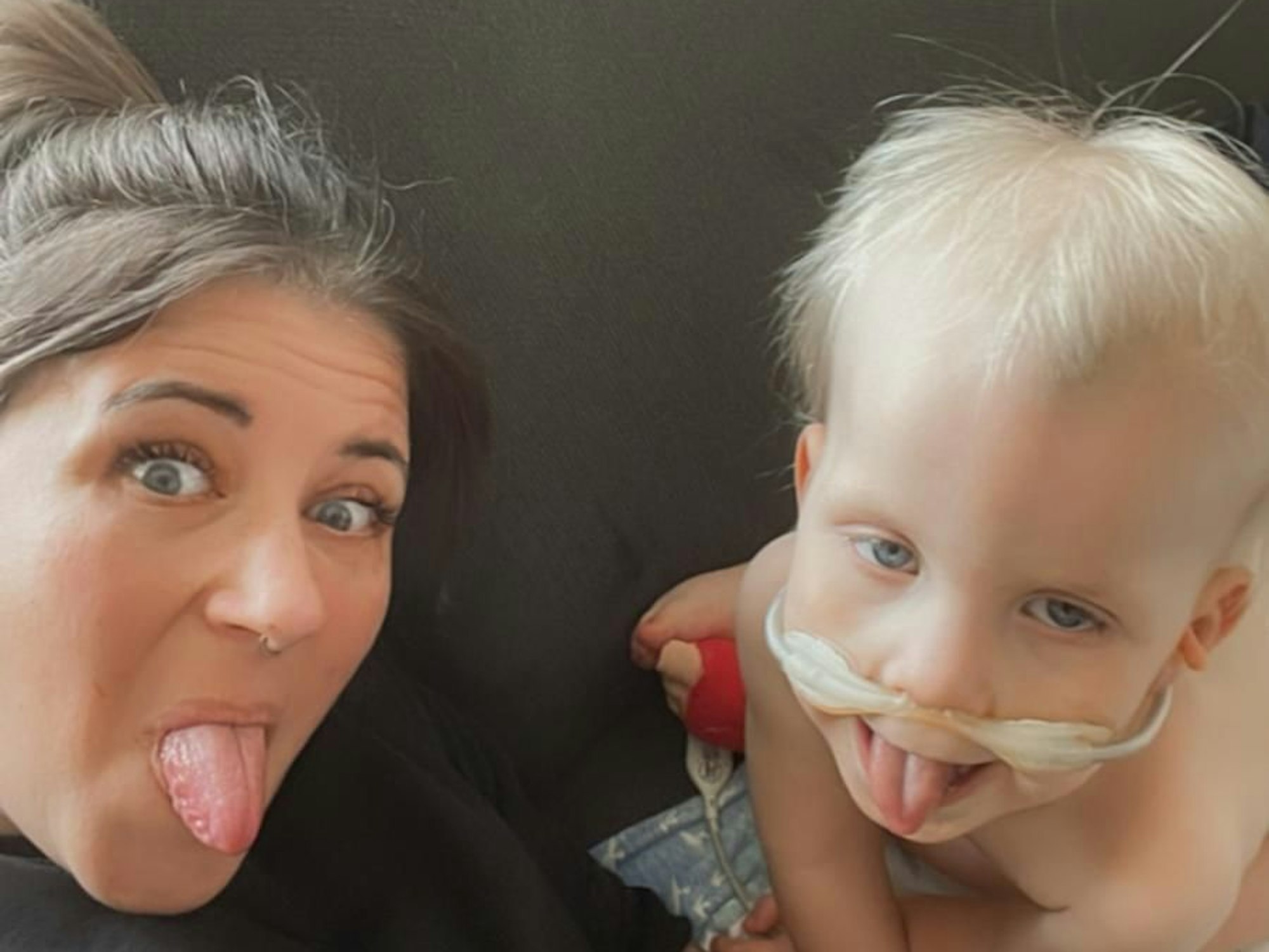 Eine Frau und ein Junge strecken für ein Foto ihre Zungen heraus.