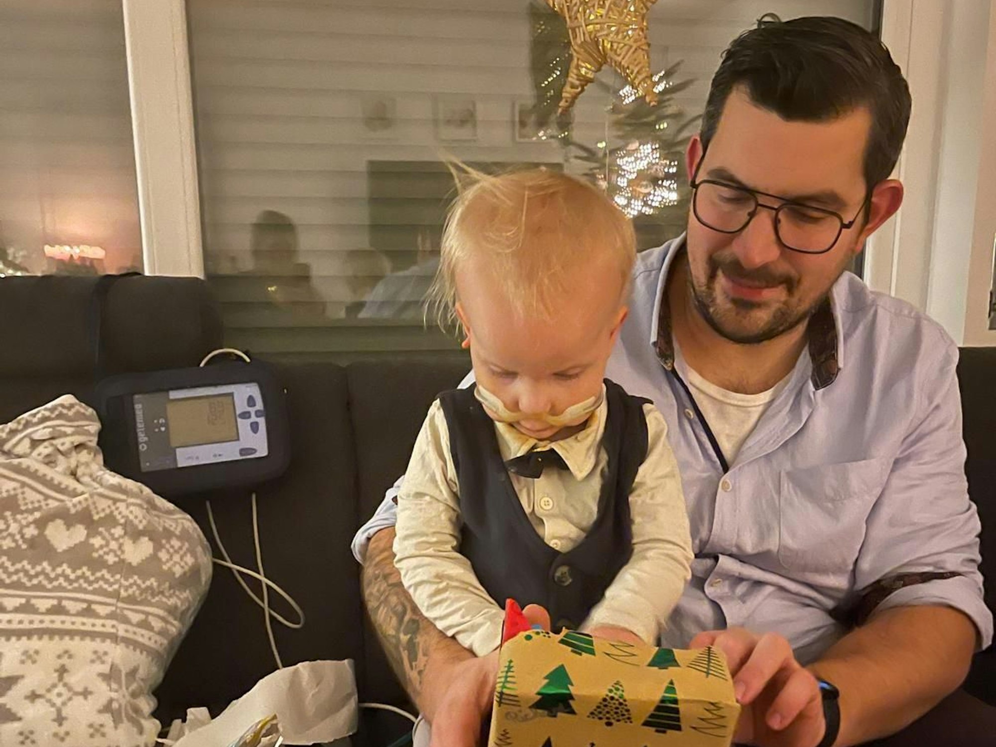 Ein Mann packt ein Geschenk mit seinem Sohn aus.