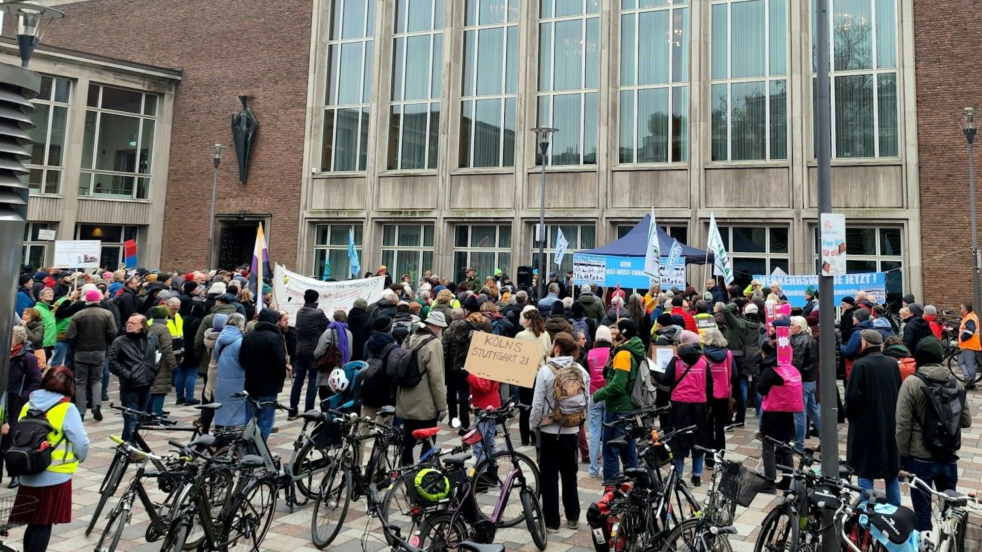 Zahlreiche Menschen stehen vor dem Rathaus, halten Plakate unter anderem mit der Aufschrift „Kein Ost-West-Tunnel“ hoch