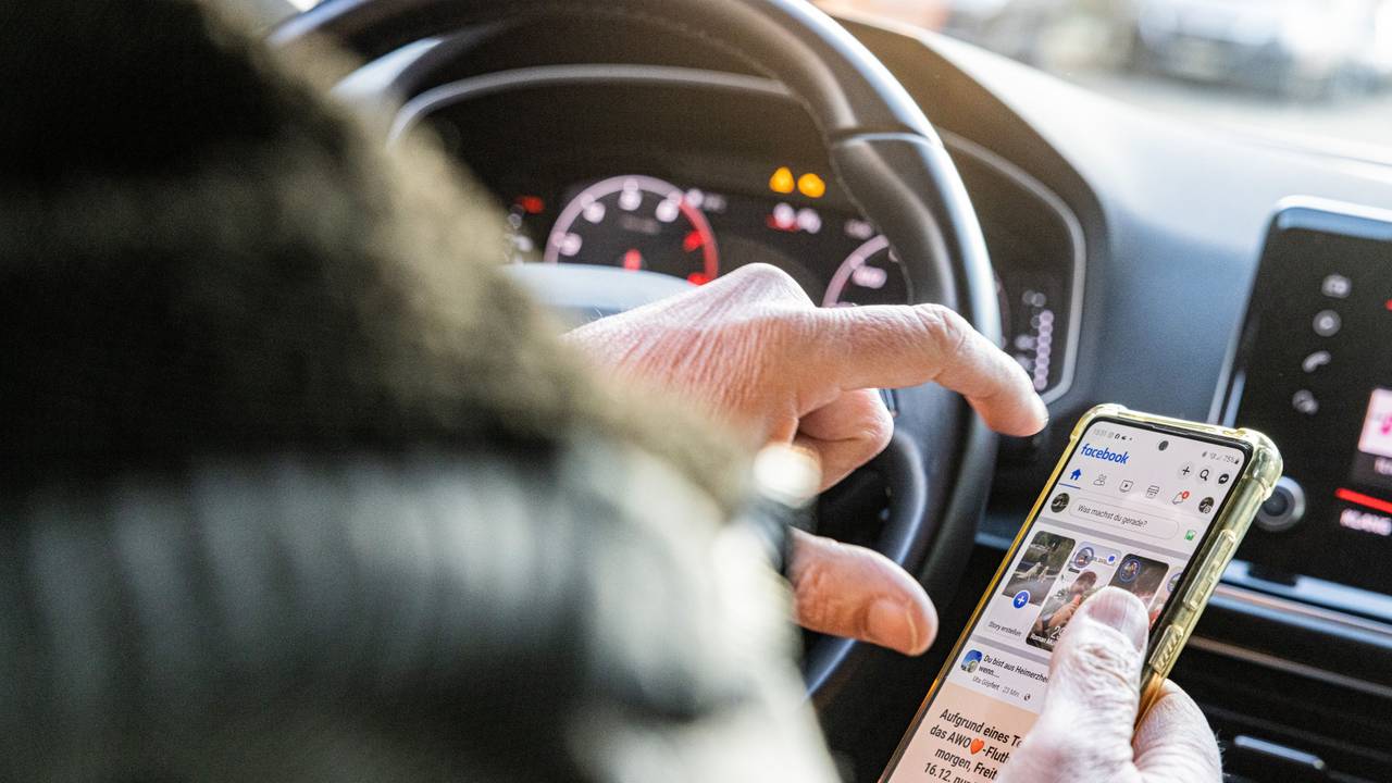 Person wird durch ihre Smartphone-Nutzung am Steuer abgelenkt.