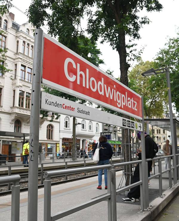 Menschen stehen an einer Straßenbahnhaltestelle in Köln.
