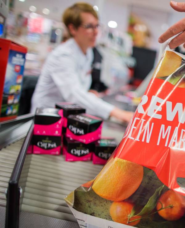 Ein Kunde packt am 31.05.2016 an der Kasse eines Rewe-Marktes in Düsseldorf (Nordrhein-Westfalen) seine Einkäufe in eine Tragetasche aus Plastik. Die Rewe Group möchte eine Reduzierung von Plastikmüll erreichen und verzichtet in Zukunft in ihren Märkten auf Plastiktüten. Foto: Rolf Vennenbernd/dpa ++ +++ dpa-Bildfunk +++