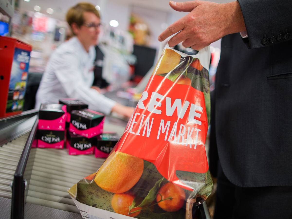 Ein Kunde packt am 31.05.2016 an der Kasse eines Rewe-Marktes in Düsseldorf (Nordrhein-Westfalen) seine Einkäufe in eine Tragetasche aus Plastik. Die Rewe Group möchte eine Reduzierung von Plastikmüll erreichen und verzichtet in Zukunft in ihren Märkten auf Plastiktüten. Foto: Rolf Vennenbernd/dpa ++ +++ dpa-Bildfunk +++