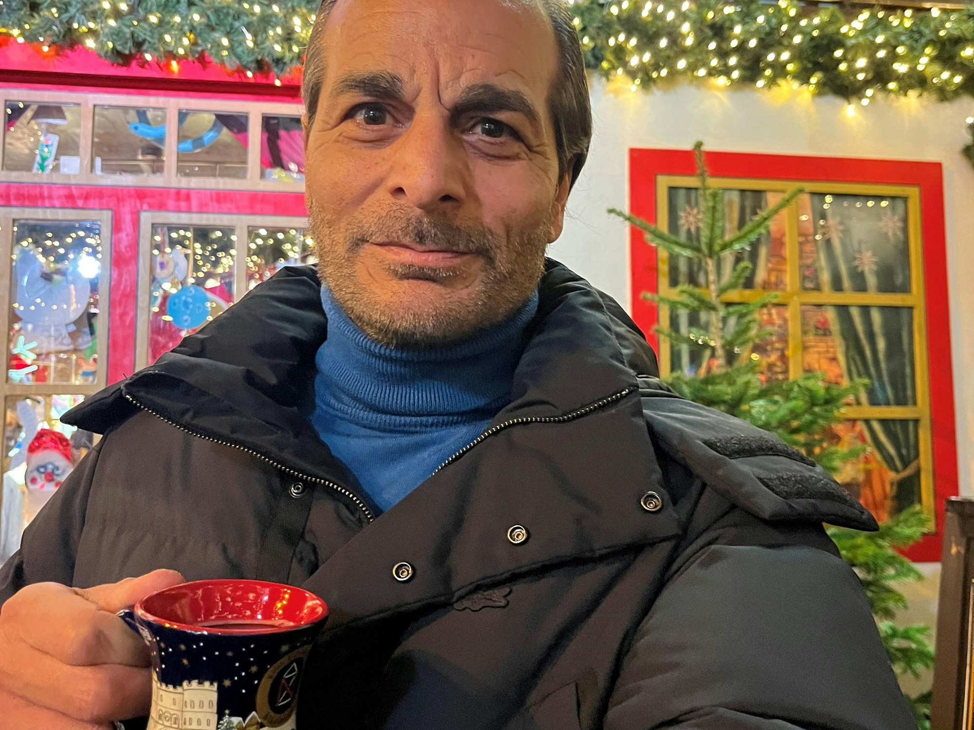 Ein Mann hält eine Glühweintasse in der Hand.