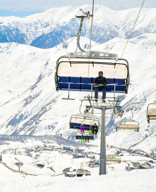 25th january, 2022 - Gudauri, Georgia: skier instructor sit on the char lift and with new Gudauri ski resort and mountains background