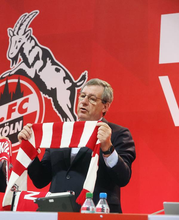 Vize Eckhard Sauren und Präsident Werner Wolf stehen mit FC-Schal auf einem Podium.