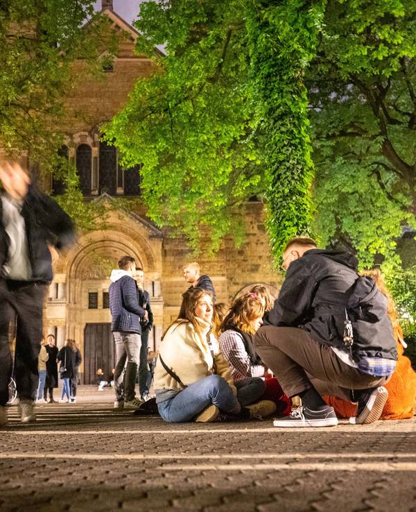Feiernde sitzen am Brüsseler Platz in Köln auf dem Boden oder feiern gemeinsam die Mai-Nacht 2022.