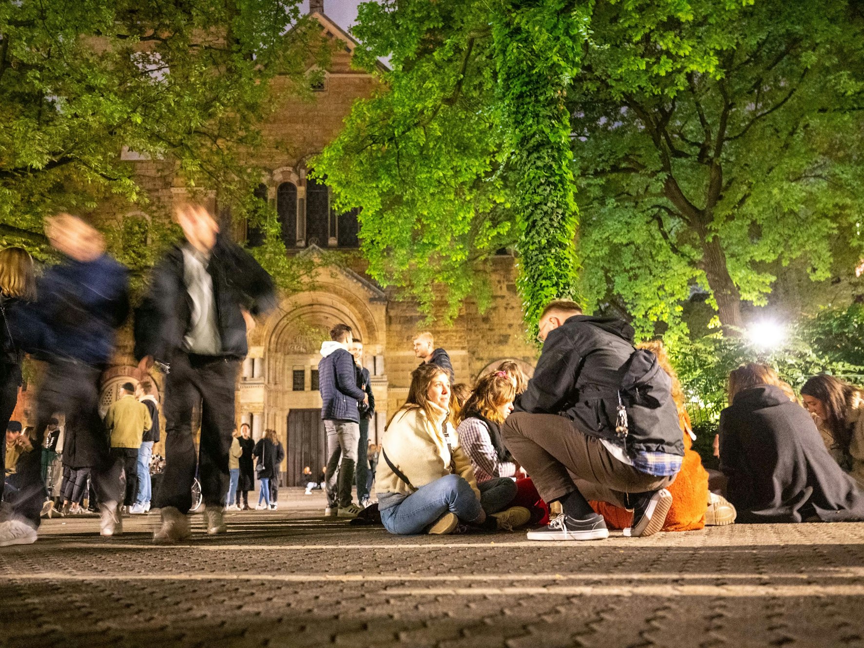 Feiernde sitzen am Brüsseler Platz in Köln auf dem Boden oder feiern gemeinsam die Mai-Nacht 2022.