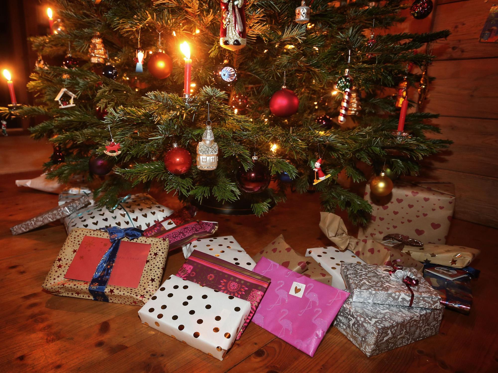 Weihnachtsgeschenke an Heiligabend liegen in einem Wohnzimmer unter einem geschmückten Weihnachtsbaum.