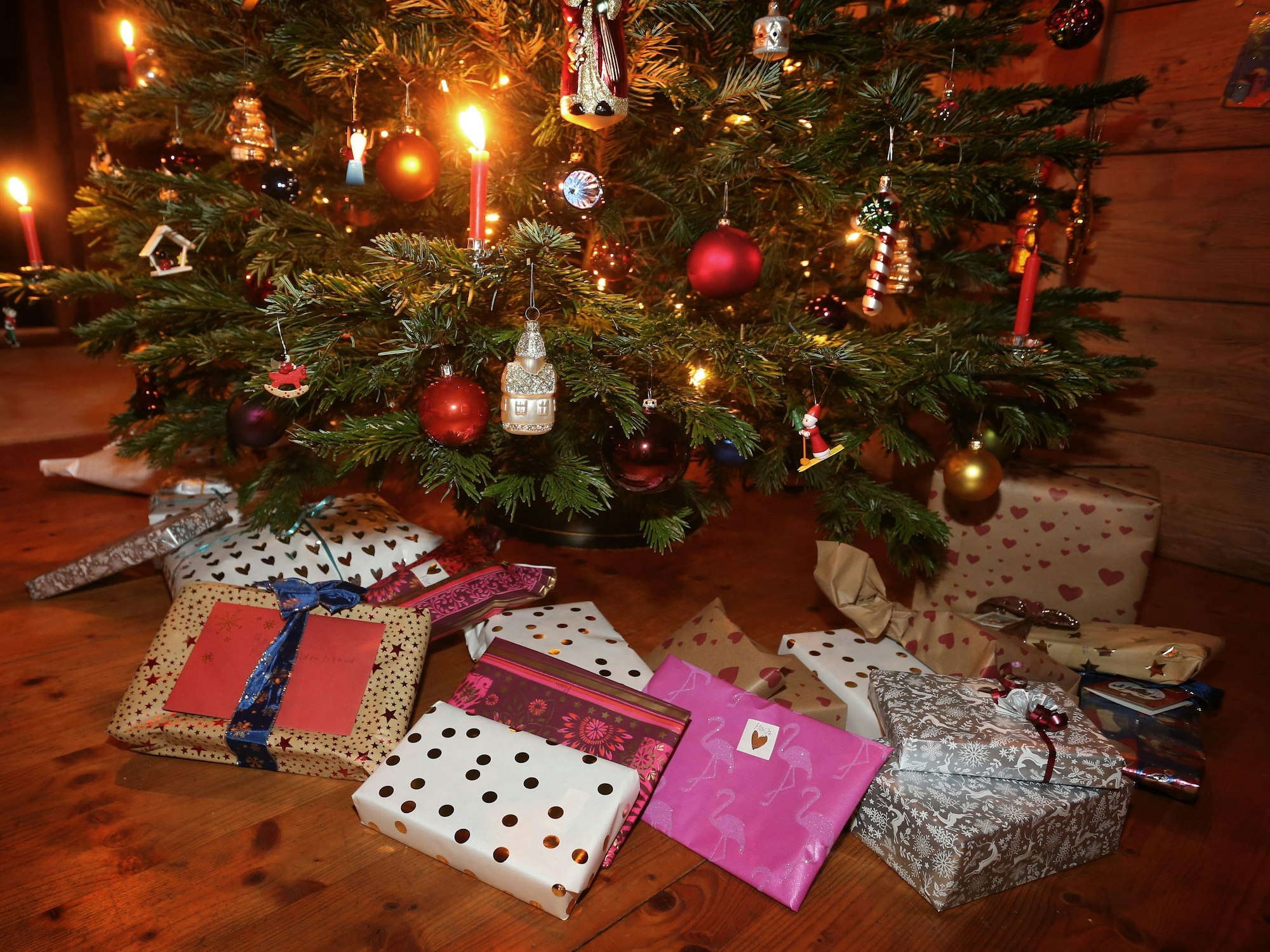 Weihnachtsgeschenke an Heiligabend liegen in einem Wohnzimmer unter einem geschmückten Weihnachtsbaum.