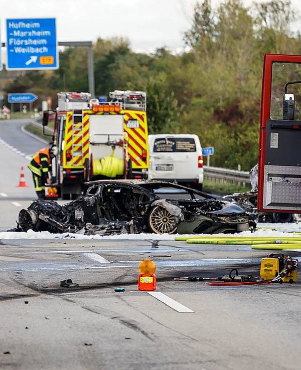 Feuerwehrfahrzeuge stehen bei einem ausgebrannten Fahrzeug auf einer Autobahn.