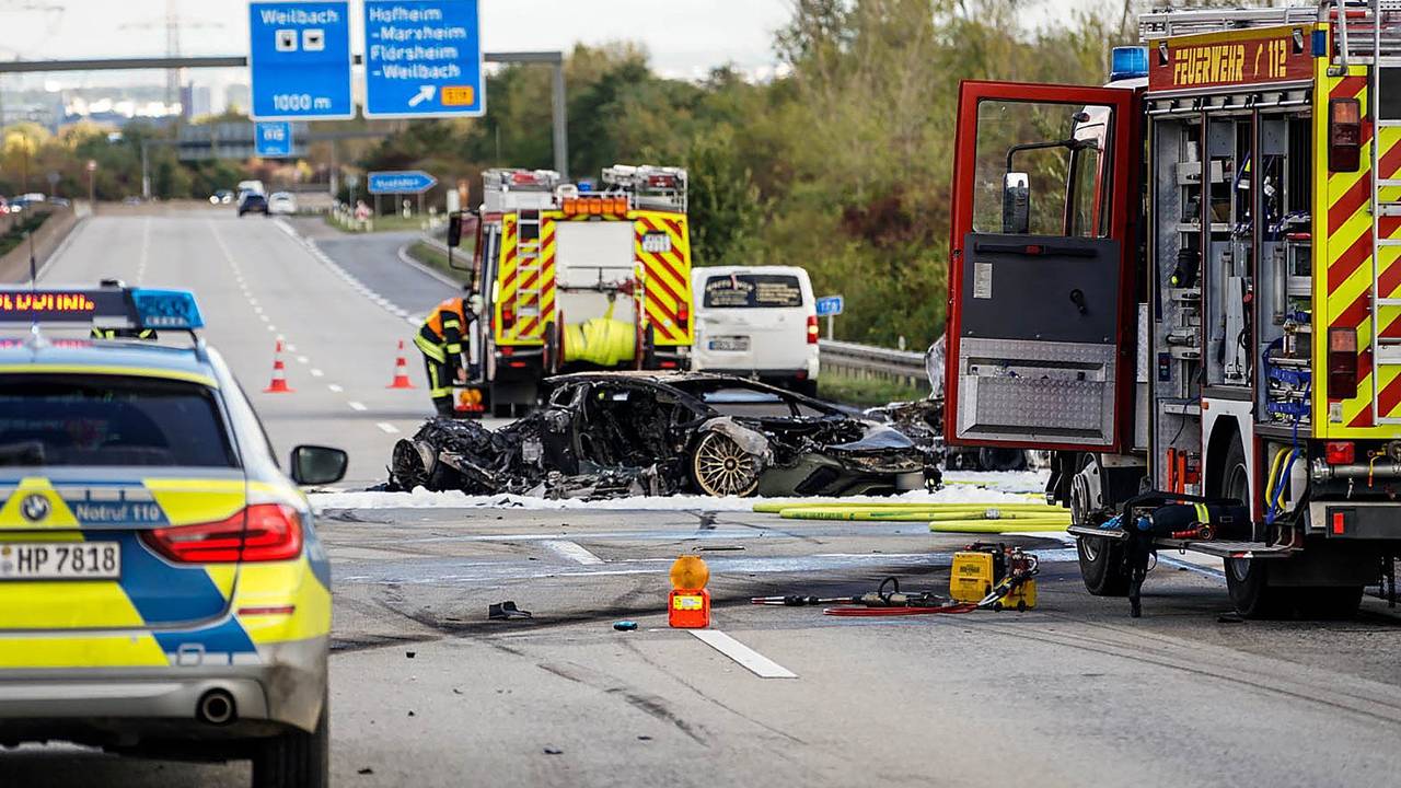 Feuerwehrfahrzeuge stehen bei einem ausgebrannten Fahrzeug auf einer Autobahn.