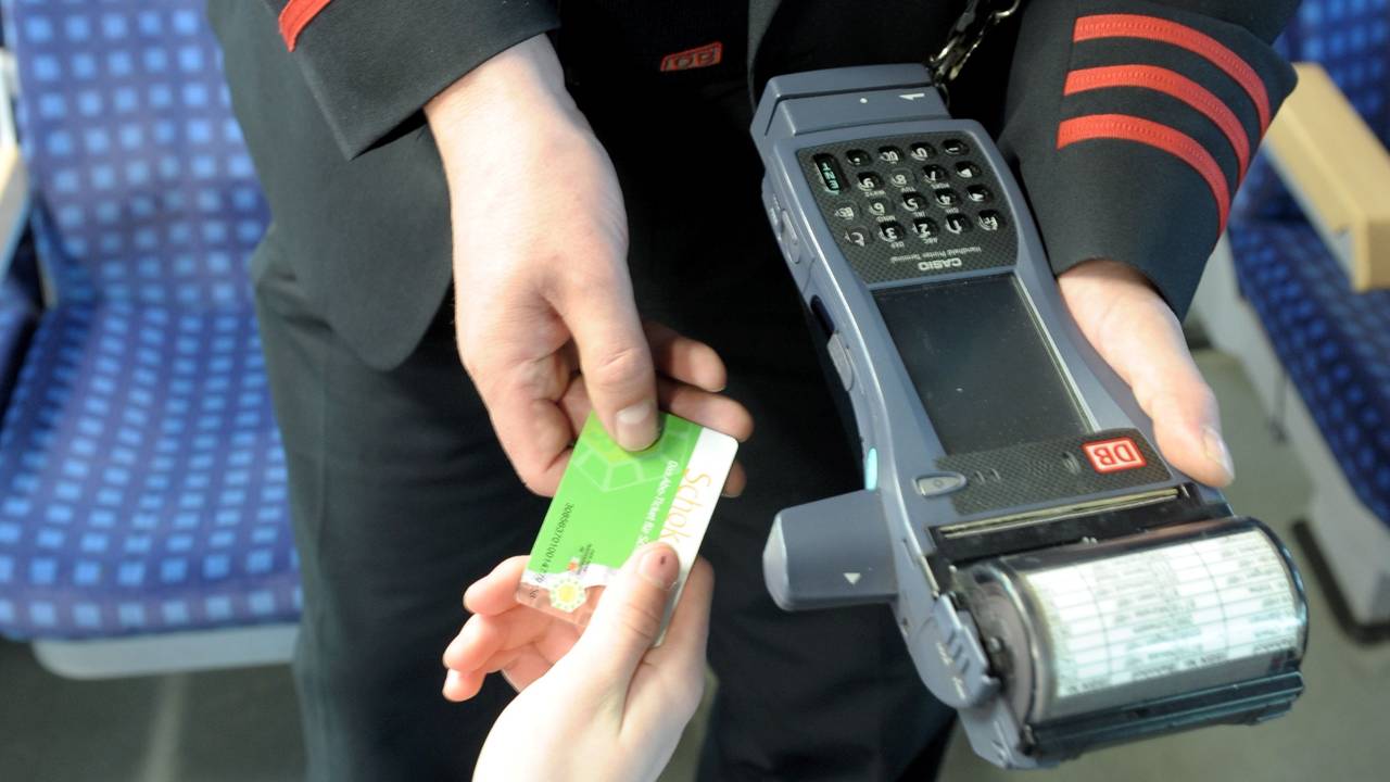 Ein Schaffner kontrolliert Fahrkarte eines Bahnkunden.