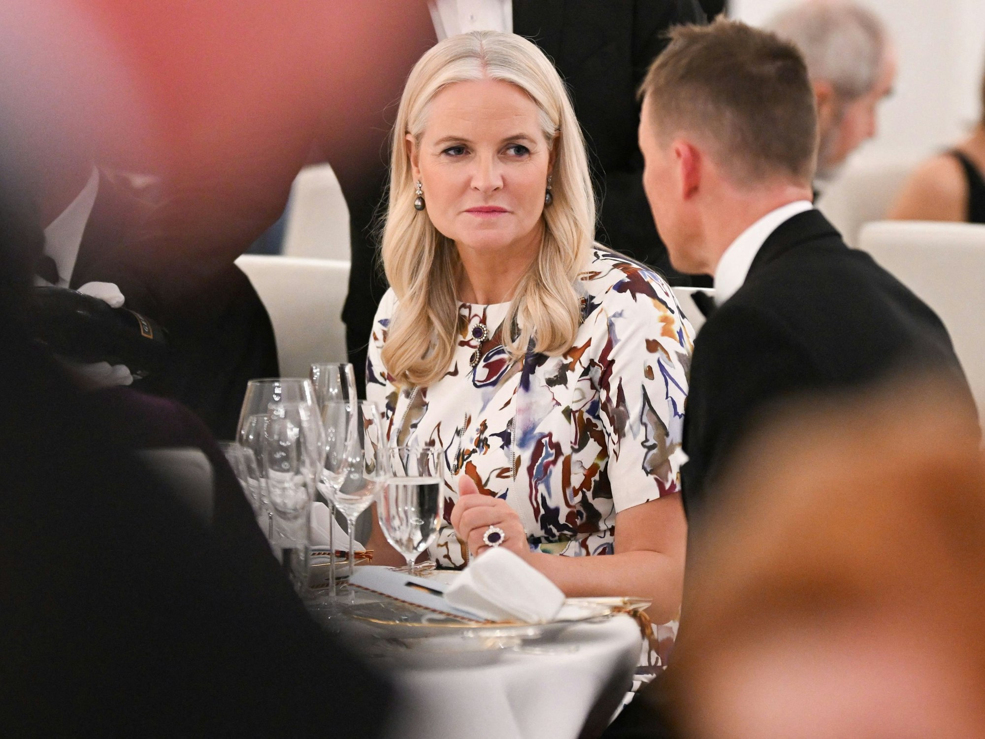 Norwegens Kronprinzessin Mette-Marit unterhält sich mit einem Mann