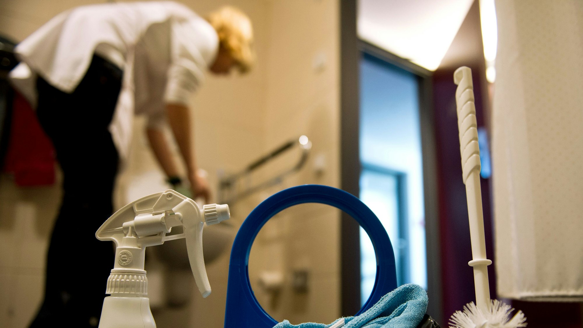Ein Zimmermädchen reinigt eine Toilette in einem Zimmer in einem Hotel.