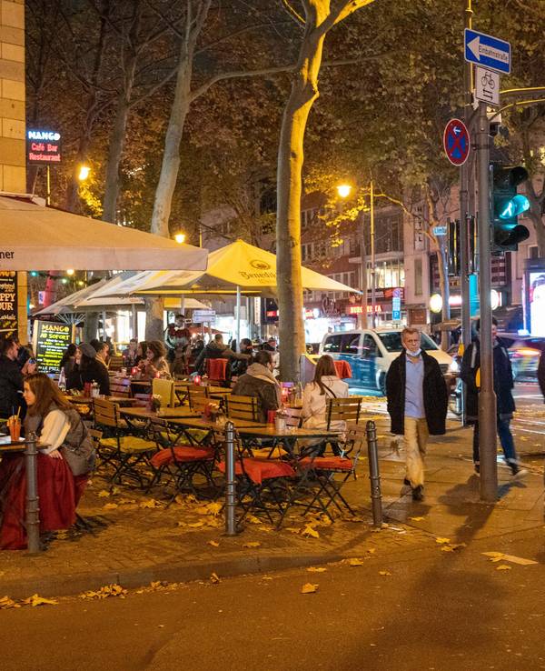 Menschen sitzen im Außenbereich eines Restaurants auf dem Hohenzollernring in Köln.