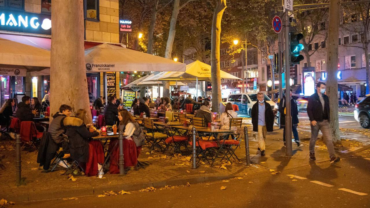Menschen sitzen im Außenbereich eines Restaurants auf dem Hohenzollernring in Köln.