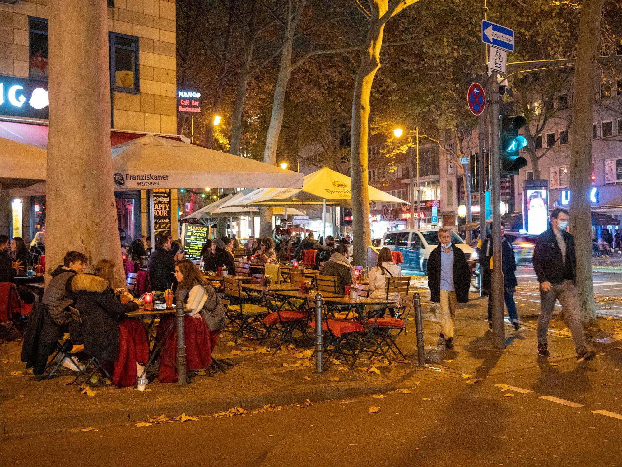 Menschen sitzen im Außenbereich eines Restaurants auf dem Hohenzollernring in Köln.