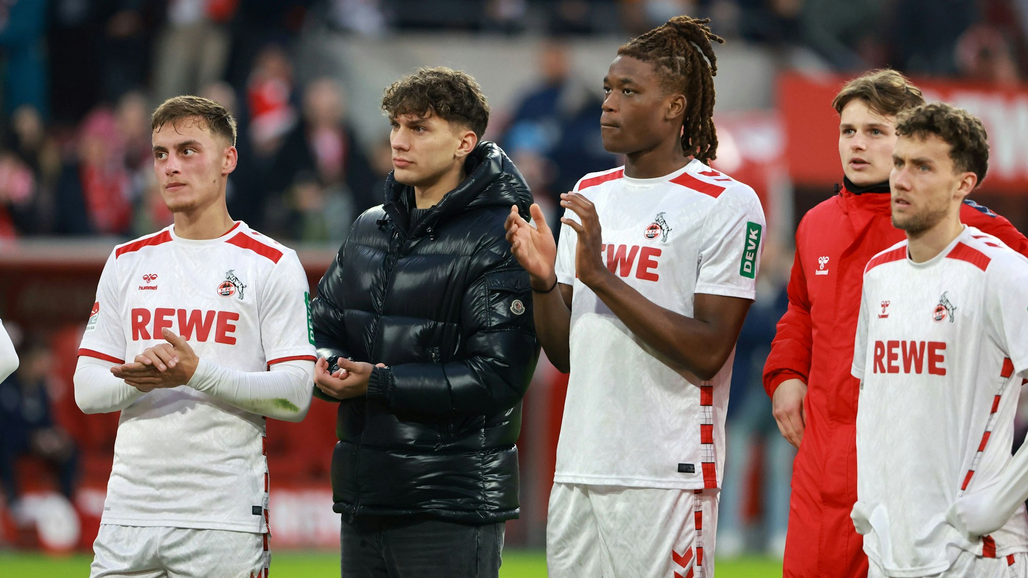 Marvin Obuz, Julian Pauli, Elias Bakatukanda, Jonas Urbig und Luca Waldschmidt stehen gemainsam vor der Fankurve des 1. FC Köln.