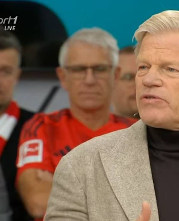 Oliver Kahn sitzt mit Sakko im Doppelpass.