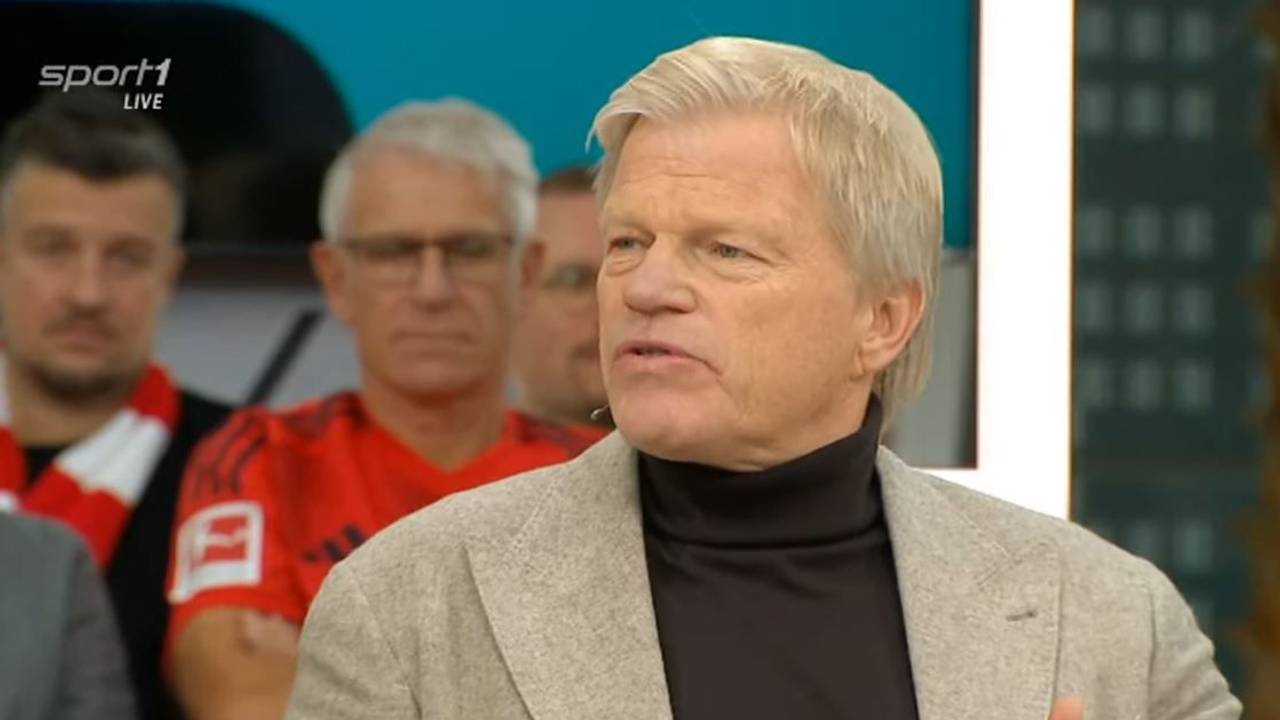 Oliver Kahn sitzt mit Sakko im Doppelpass.