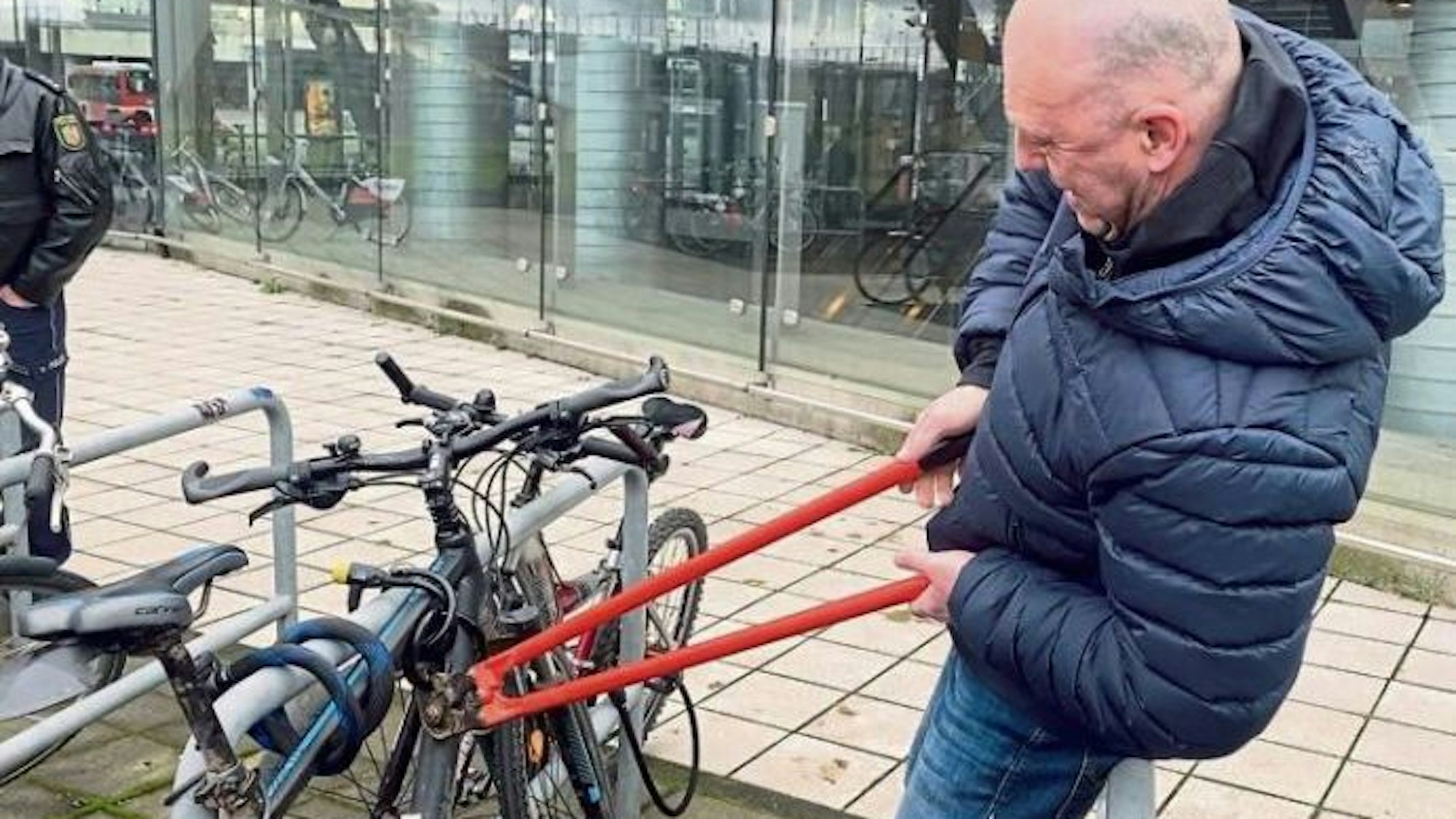Ein Mann macht sich mit einem Bolzenschneider an einem Fahrradschloss zu schaffen.