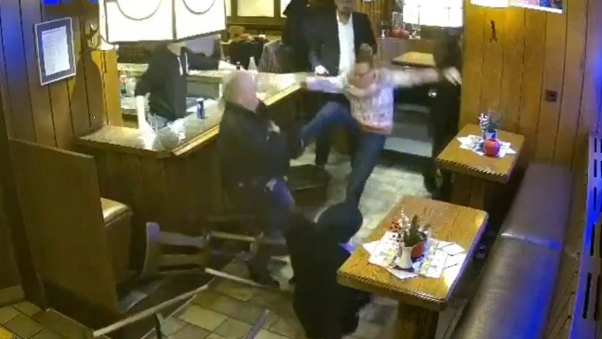 Ein Mann tritt in einer Kneipe nach einem anderen Mann.