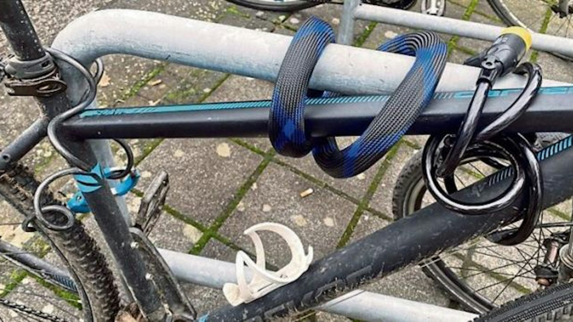 Ein Fahrrad ist mit drei Schlössern an einem Fahrradständer gesichert.