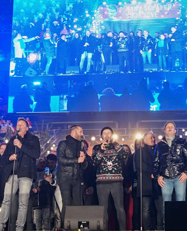 Einige Sängerinnen und Sänger stehen auf der Bühne beim Weihnachtskonzert im Rhein-Energie-Stadion in Köln.