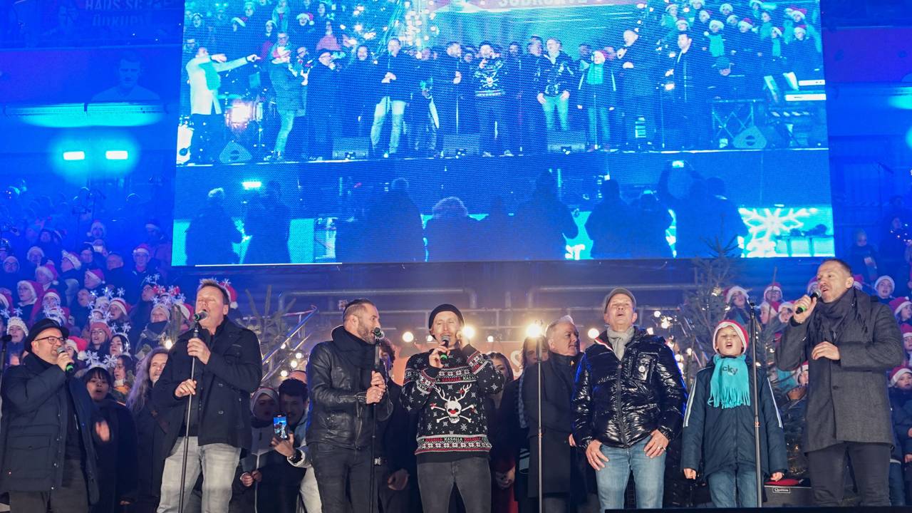 Einige Sängerinnen und Sänger stehen auf der Bühne beim Weihnachtskonzert im Rhein-Energie-Stadion in Köln.