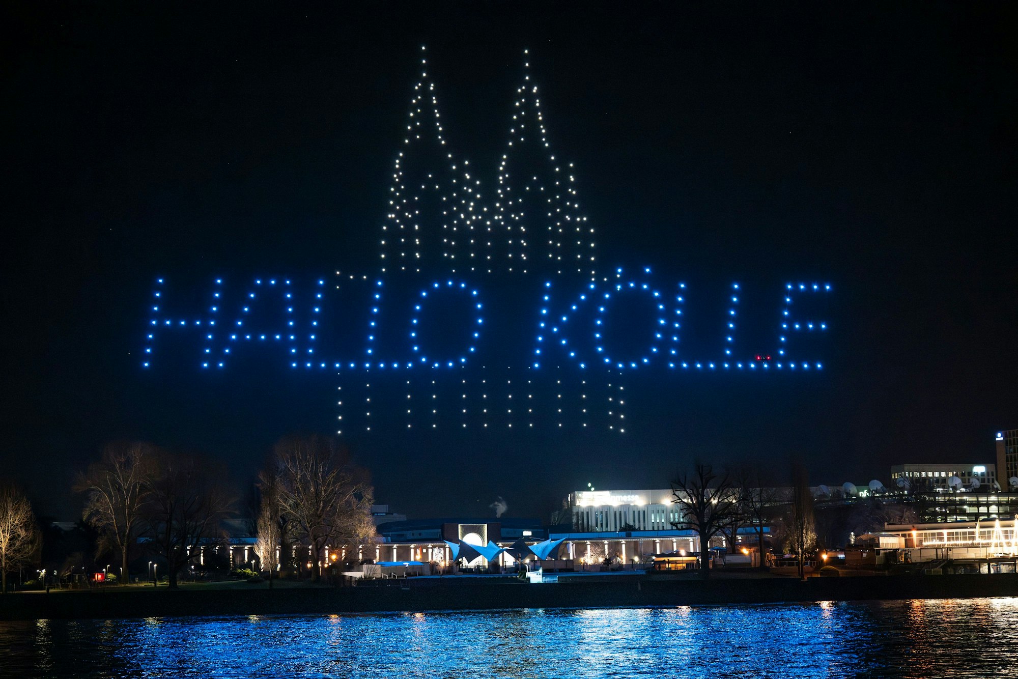 Am Nachthimmel über dem Rhein leuchten Bilder einer Drohnenshow. Es handelt sich um eine PR-Aktion des Discounters Penny.