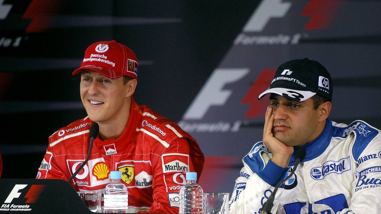 Michael Schumacher lächelt bei einer Pressekonferenz, Juan Pablo Montoya sietzt gelangweilt daneben.