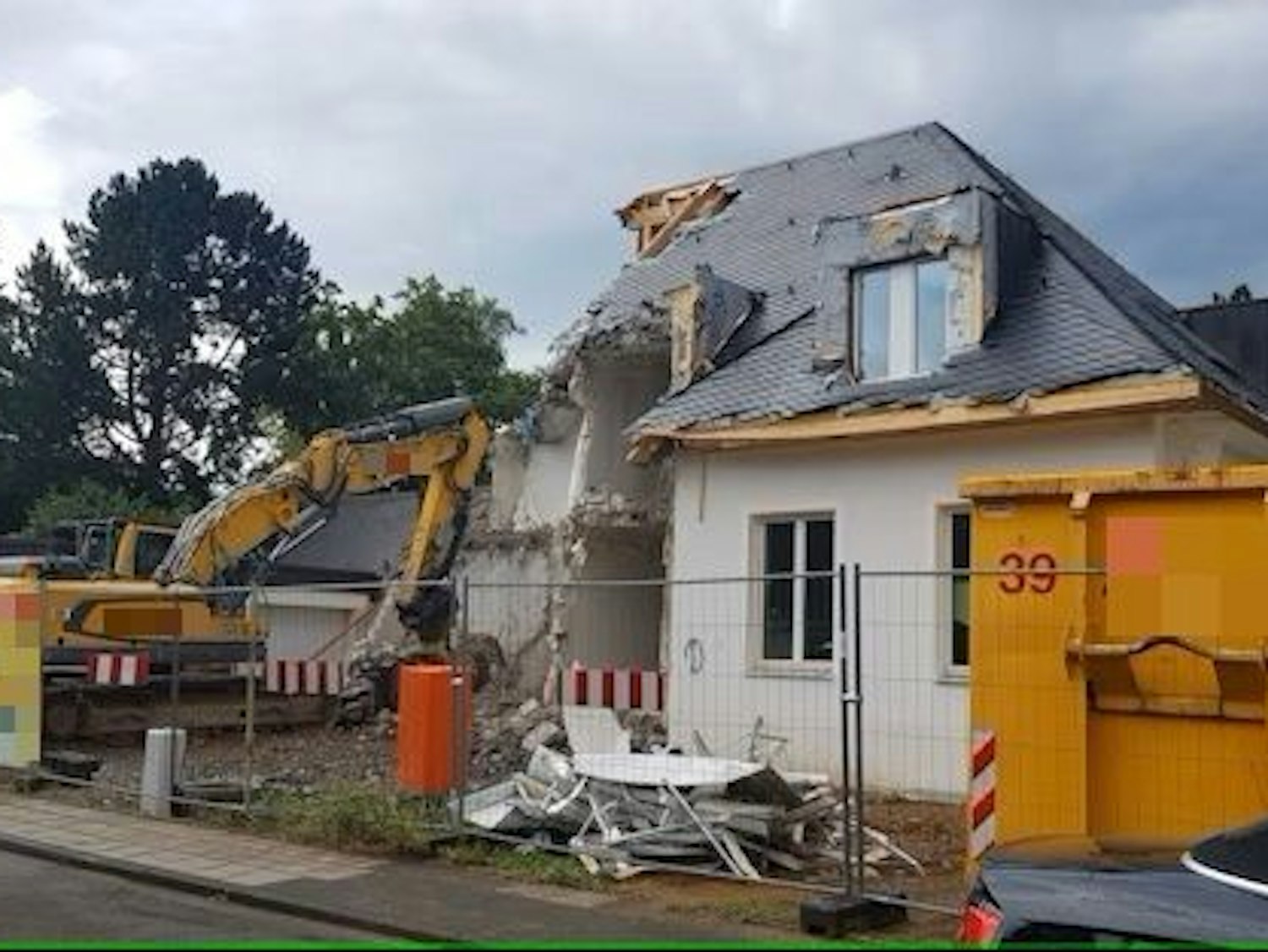 Ein Bagger reißt ein Haus ein.