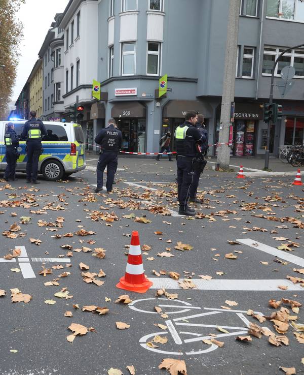 Polizeikräfte und zwei Polizeiwagen stehen auf einer Kreuzung.