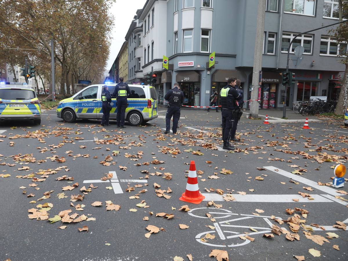 Polizeikräfte und zwei Polizeiwagen stehen auf einer Kreuzung.
