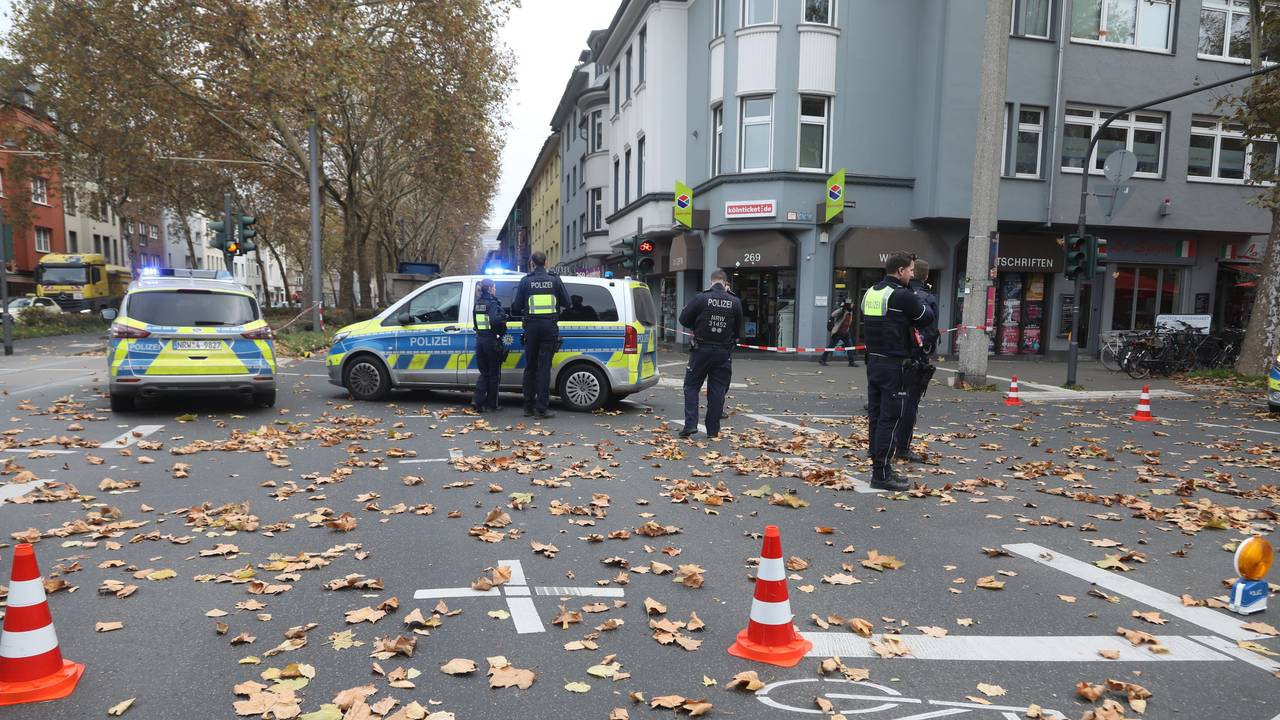 Polizeikräfte und zwei Polizeiwagen stehen auf einer Kreuzung.