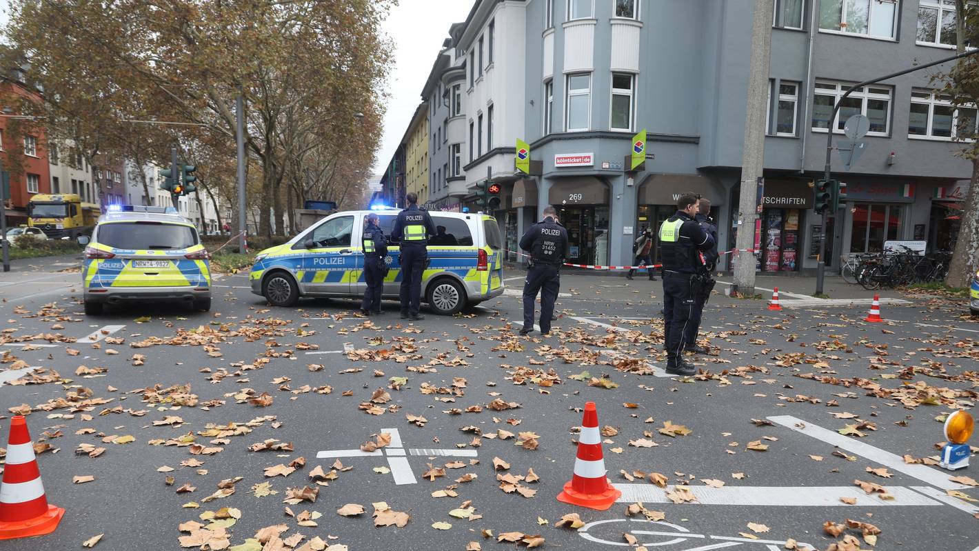 Polizeikräfte und zwei Polizeiwagen stehen auf einer Kreuzung.
