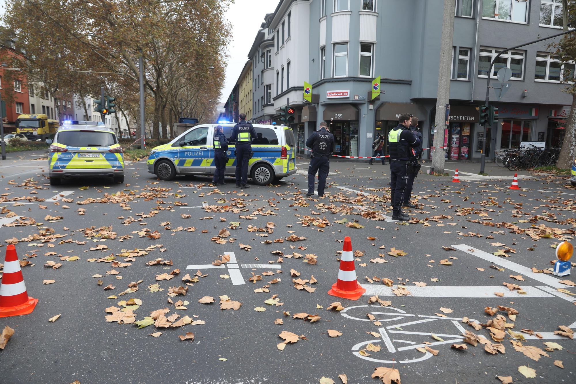 Polizeikräfte und zwei Polizeiwagen stehen auf einer Kreuzung.