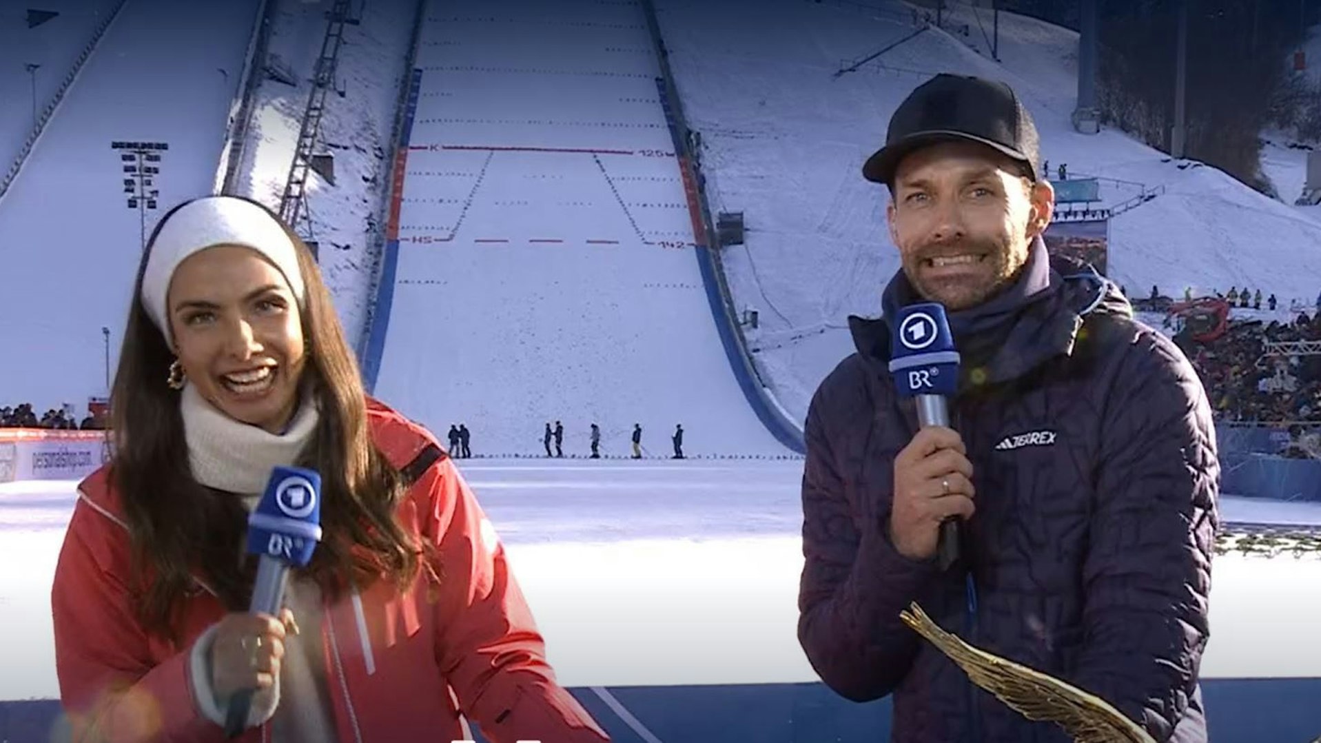 Lea Wagner lacht, während Sven Hannawald peinlich berührt Richtung Kamera blickt.