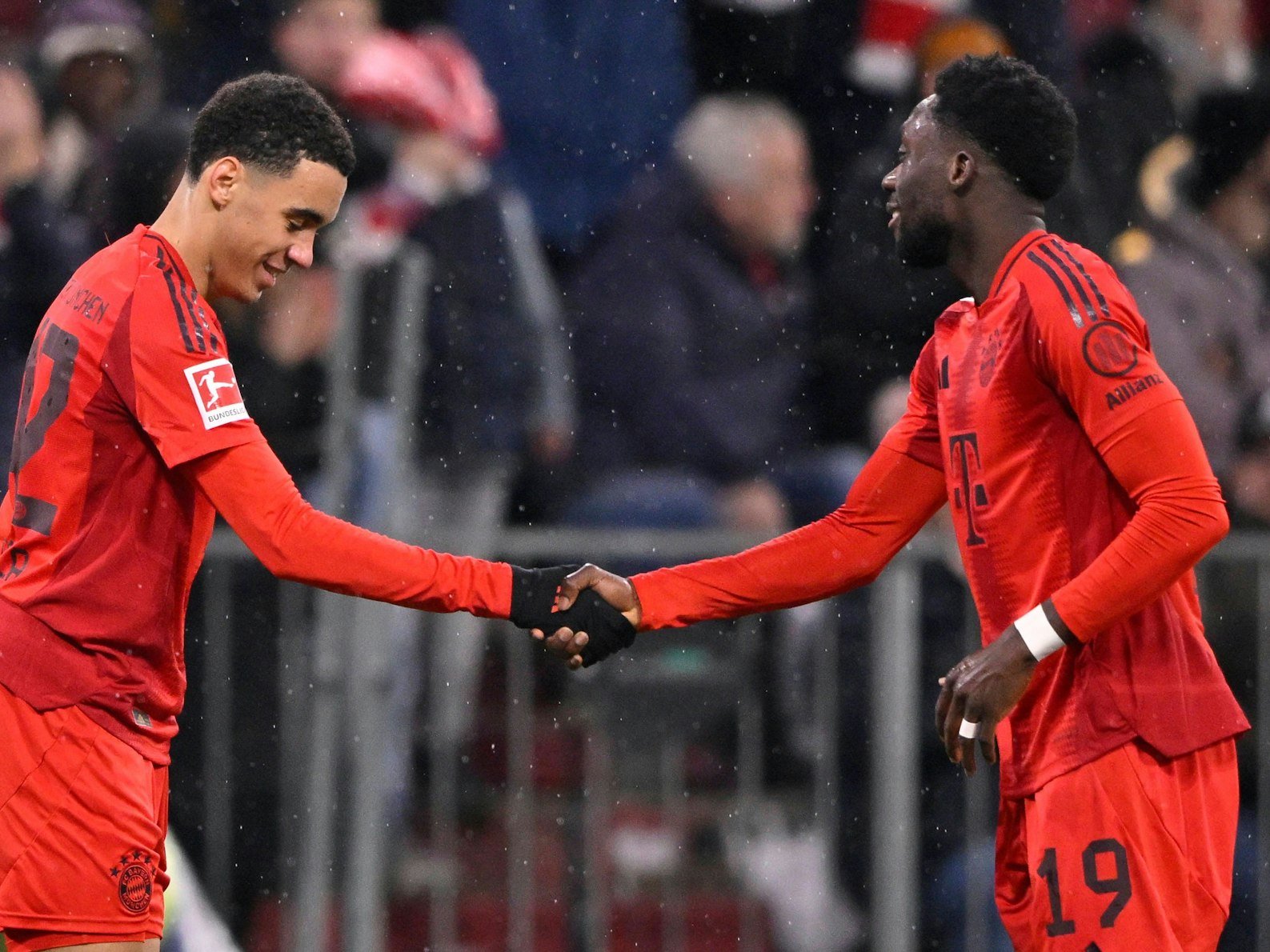 Jamal Musiala und Alphonso Davies mit Handshake nach einem Tor.