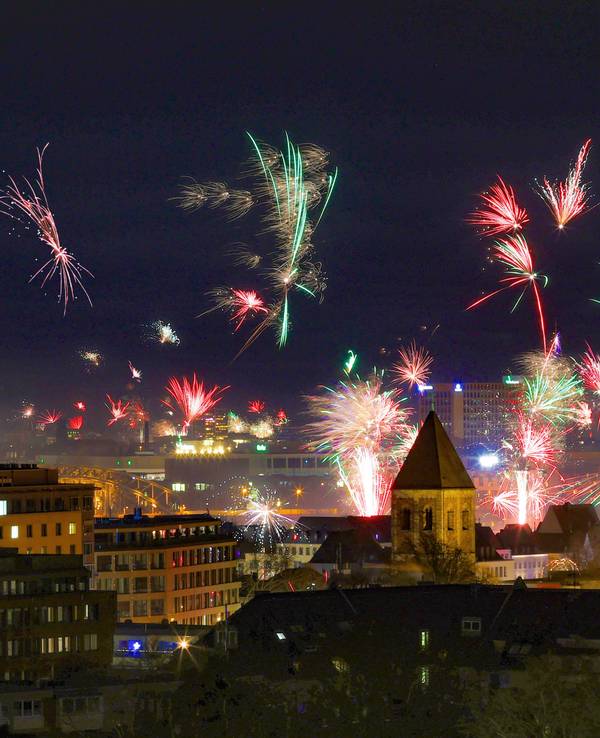 In der Silvesternacht erstrahlt über der Kölner Altstadt ein Feuerwerk am Rhein.