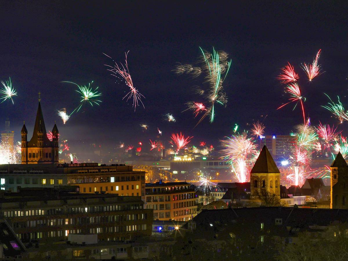In der Silvesternacht erstrahlt über der Kölner Altstadt ein Feuerwerk am Rhein.