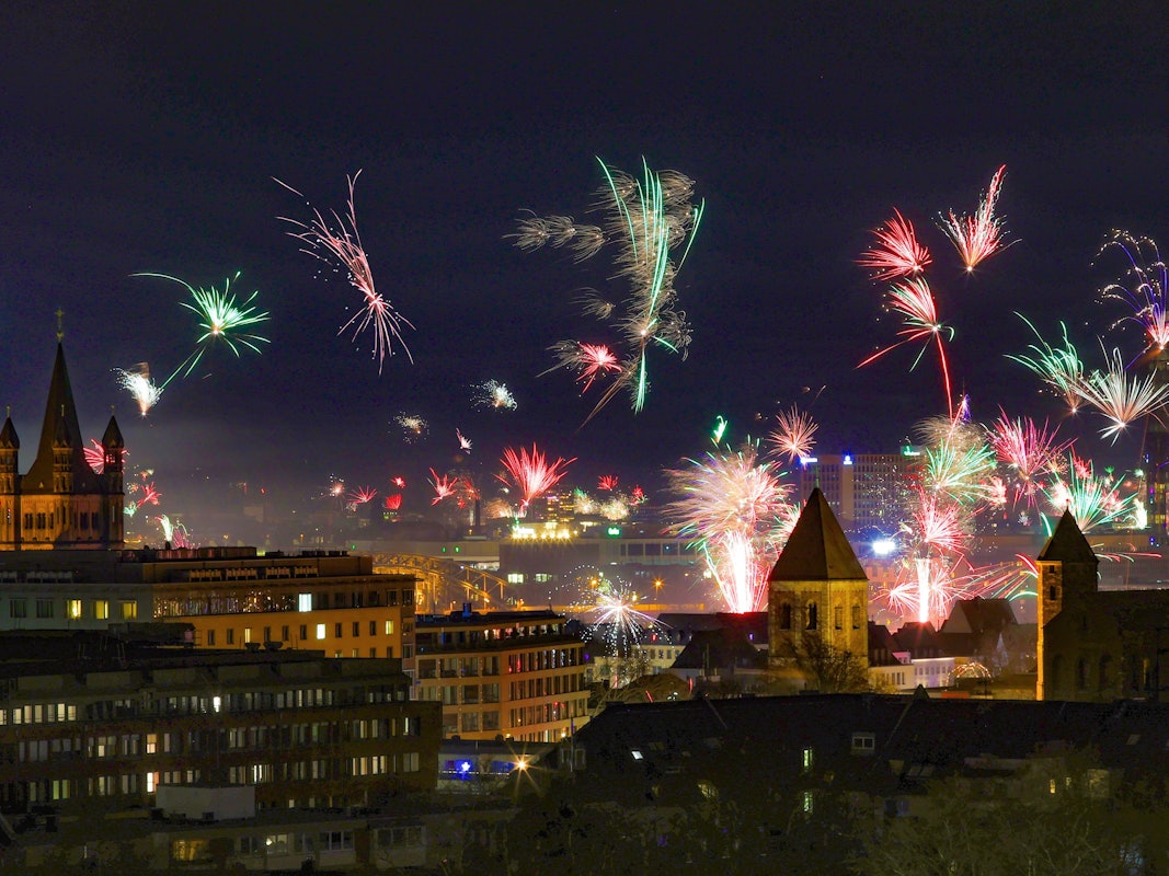 In der Silvesternacht erstrahlt über der Kölner Altstadt ein Feuerwerk am Rhein.