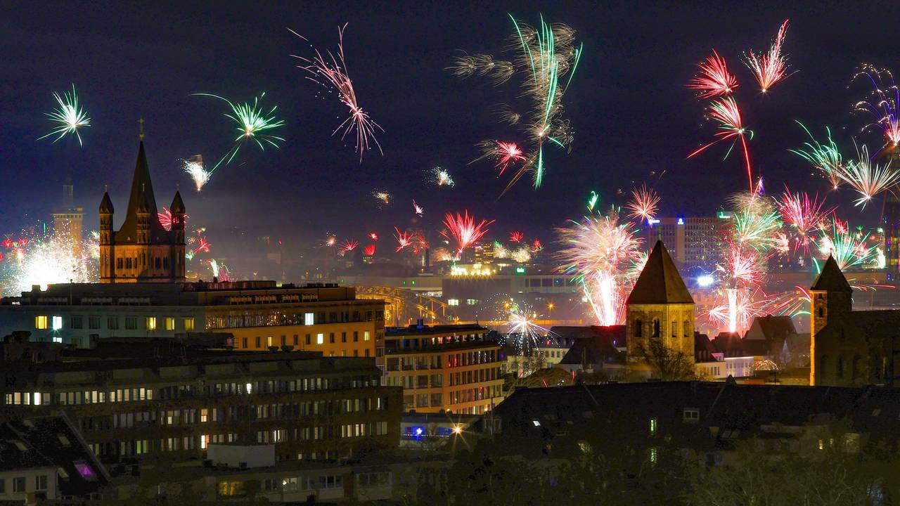 In der Silvesternacht erstrahlt über der Kölner Altstadt ein Feuerwerk am Rhein.