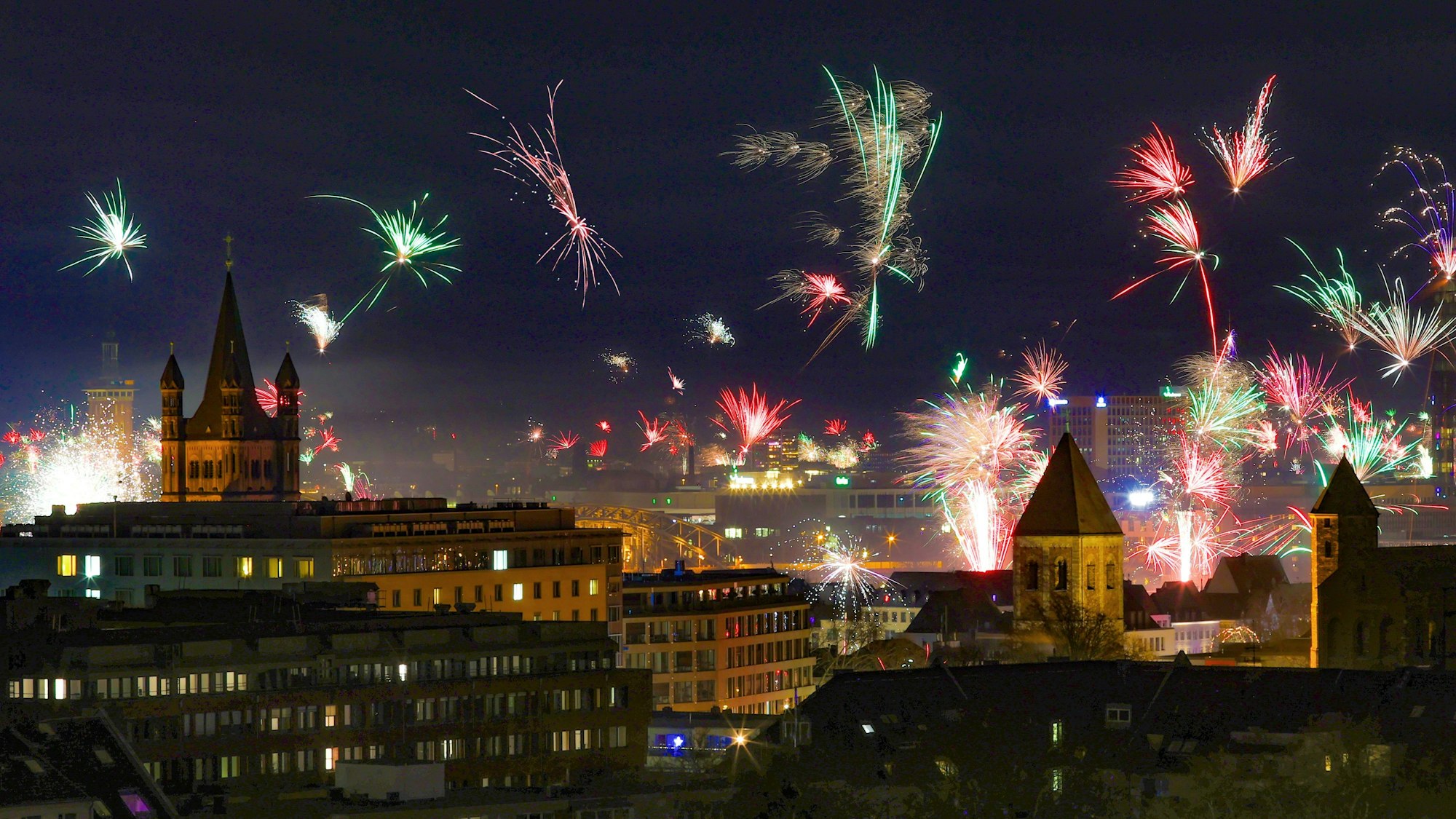 In der Silvesternacht erstrahlt über der Kölner Altstadt ein Feuerwerk am Rhein.