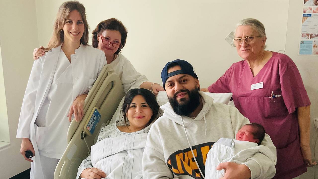 Eine Gruppe mit einem Baby posiert im Krankenhaus für ein Foto.