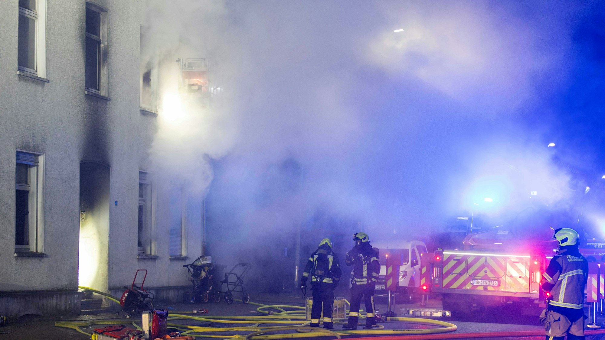 Einsatzkräfte der Feeurwehr löschen den Brand in einem Mehrfamilienhaus. Bei einem Feuer in einem Mehrfamilienhaus sind in Gelsenkirchen mehrere Menschen verletzt worden.