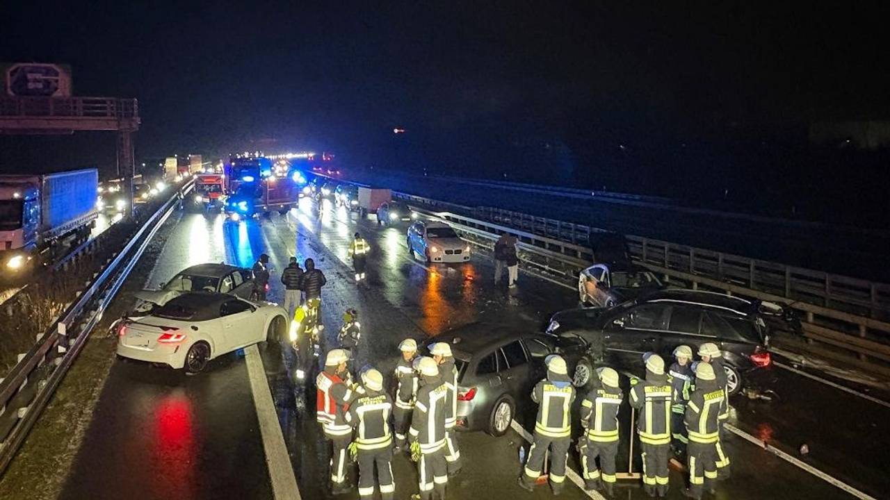 Mehrerer Feuerwehrleute stehen nachts auf der Fahrbahn einer Autobahn, vor ihnen mehrere verunfallte Autos.