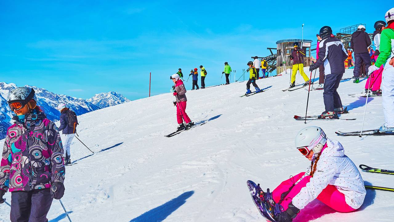 GThe skiers going downhill from top of Zwieselalm mountain (Dachstein West) and young girl attaches bindings of snowboard to the boots, on February 26 in Gosau.